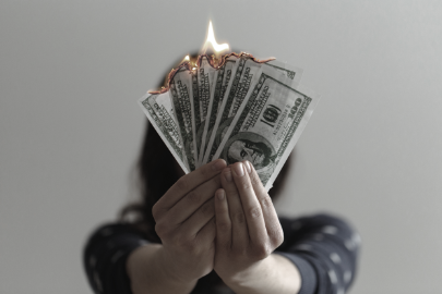 Woman holding up dollar bills that are on fire